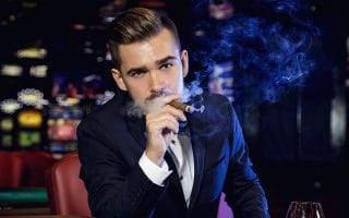 A Man in a Black Suit Smoking a Cigar